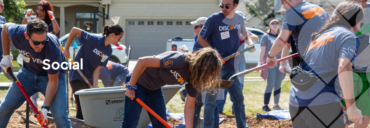 Discover employees outdoors, digging with shovels and wearing matching company tee shirts.
