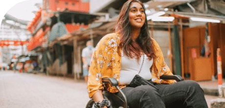 A woman in a wheelchair travelling alone on a street