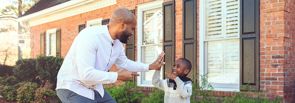 A father and son give each other a high five outside of their home