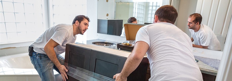 Two contractors installing a new vanity as part of a low cost bathroom remodel project