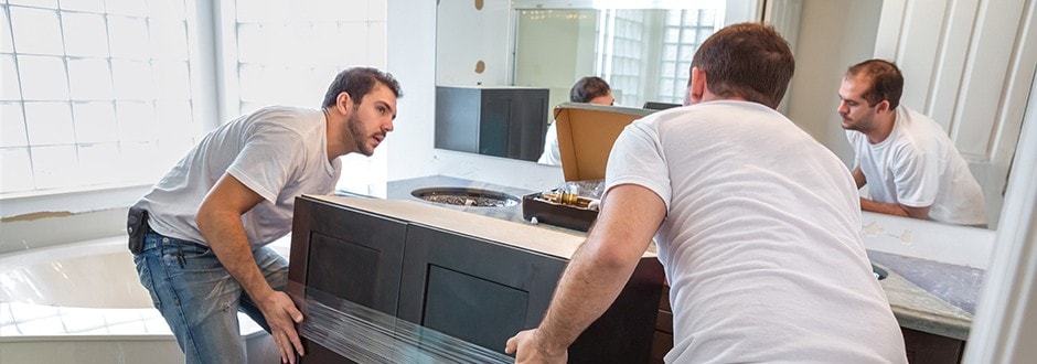 Two contractors remodeling a bathroom with a new vanity installation