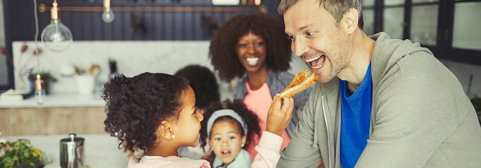 Parents and their three kids eating pizza and enjoying their home that has built equity