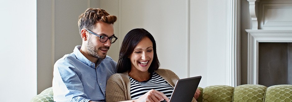 A couple on their sofa, looking up refinancing options and HELOC details together