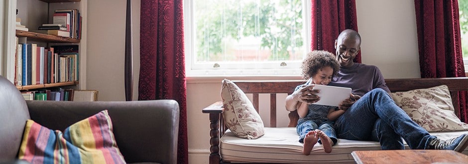 Father and son with tablet on their couch in their home that has built home equity