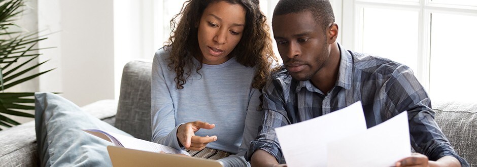 Young couple with computer and home purchase contract in hand discussing if it is a good time to walk away.
