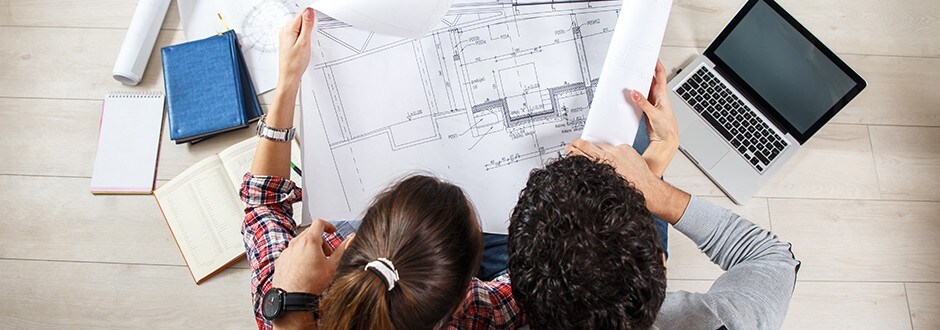 : Family sitting in living room reviewing building plans for the house that they are building