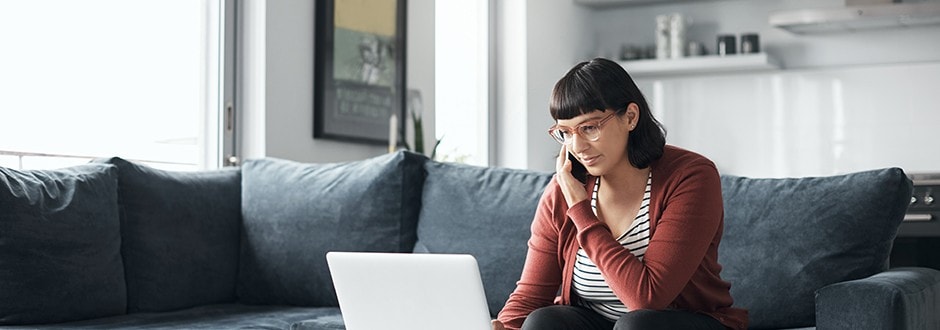 A young woman talking on her cellphone while comparing the best home improvement loan rates on her laptop