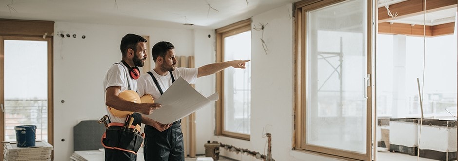 Two contractors planning a home improvement project with construction equipment and plans