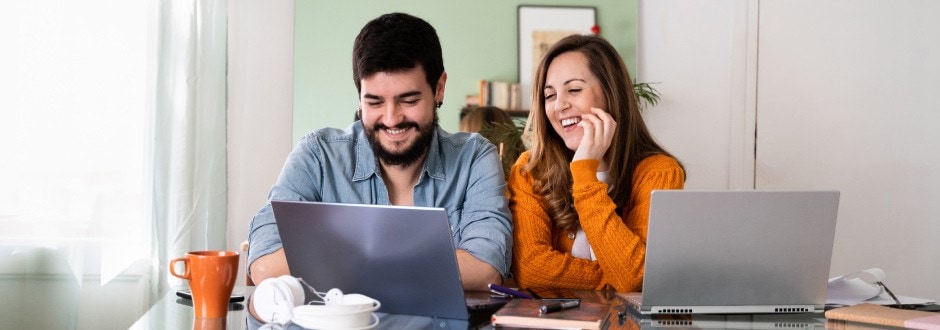 Young couple smiles happily as they review their home refinancing options and see how they can save on their home mortgage