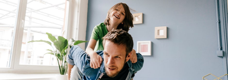 Happy father carrying son piggyback at home