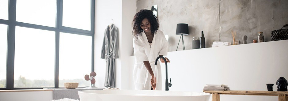 Woman in her modern style master bathroom that she remodeled within her budget