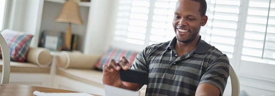 A man using his mobile phone to check the benefits and the comparison of personal loans and home equity loans.