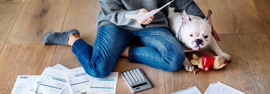 Woman sitting with her dog, calculating the pros and cons of loan consolidation