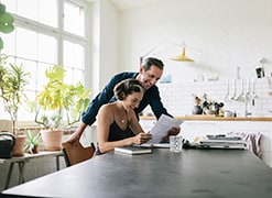 Happy mature couple reading a document. The couple is sitting in the kitchen.