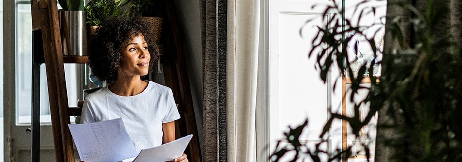 Woman looking out the window while she compares home refinancing rates in California