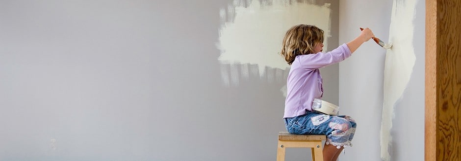 Young child helping with remodeling her Mediterranean style home by painting a wall