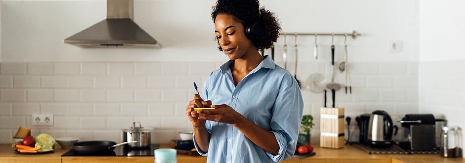 Woman in her kitchen in the morning writing notes