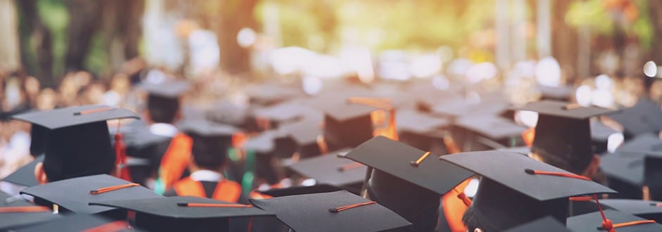 Group of college students stand at their graduation ceremony, having financed their education through various funding options