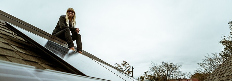 Woman sitting on her roof with newly installed solar panels