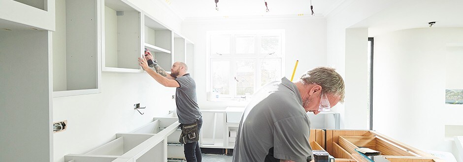 Construction workers installing cabinets in a kitchen that has been well thought out and funded using helpful tools