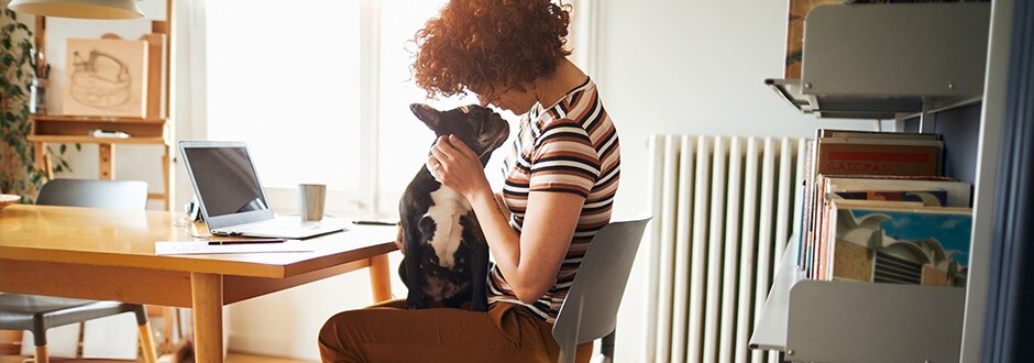 Woman playing with her dog while taking a break from calculating her debt-to-income ratio