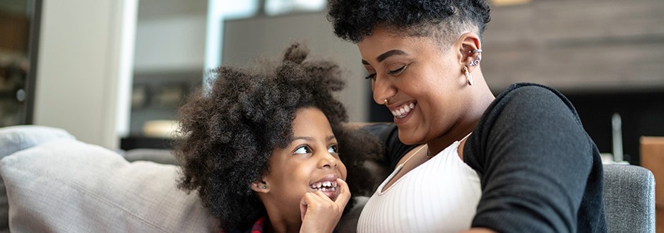 Young woman spending time with her child while using her phone to compare HELOC fees