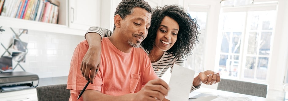 Couple with documents researching what they need to know before buying a foreclosed home