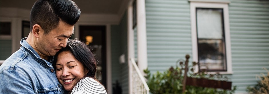 Young couple in front of a home that they recently purchased