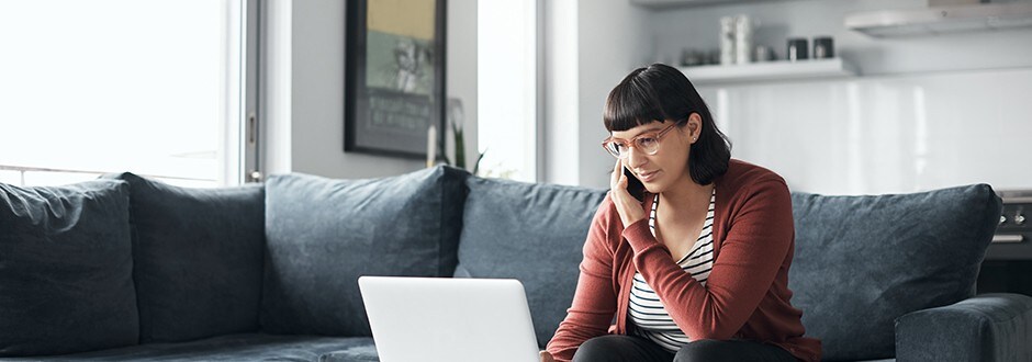 Woman on the phone in her home deciding when to replace her car and comparing options to pay for it.