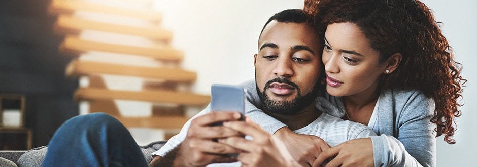 Couple looking at a phone considering the different ways to borrow money and the pros and cons of each