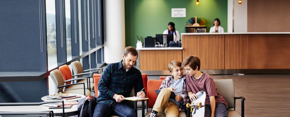 A father and two kids wait in a waiting room.