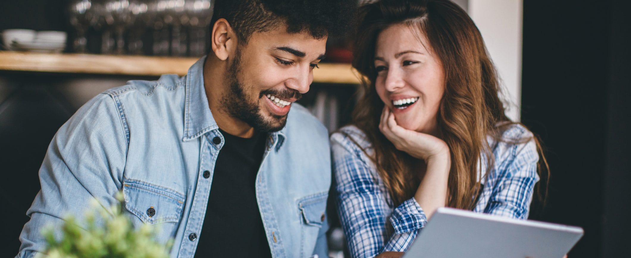 A man and a woman review their financial resolutions together, sharing a tablet computer.