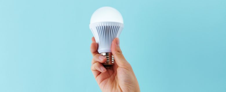 A hand holding a low-power LED lightbulb.