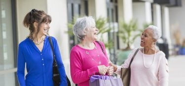 Group of three women laughing outside.