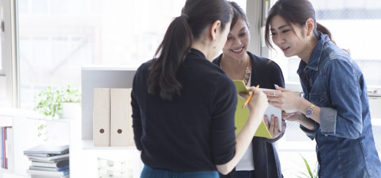 Three coworkers reviewing meeting notes in the office