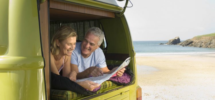 Retired couple sitting in the back of a van, planning a road trip
