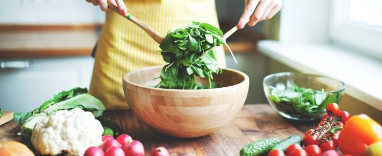 Closeup of hands tossing a healthy green salad.