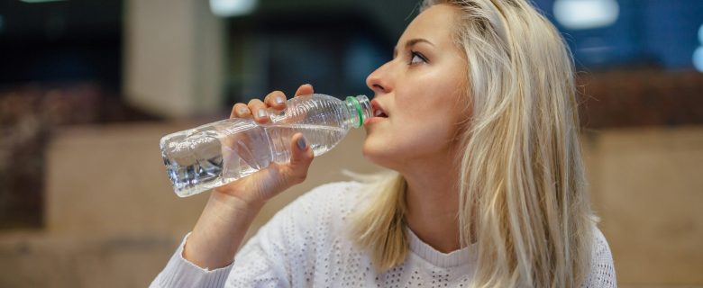  A young woman drinking from a bottle of water.