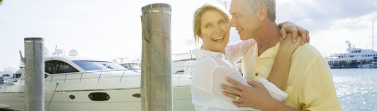 Couple standing on dock in front of a small yacht