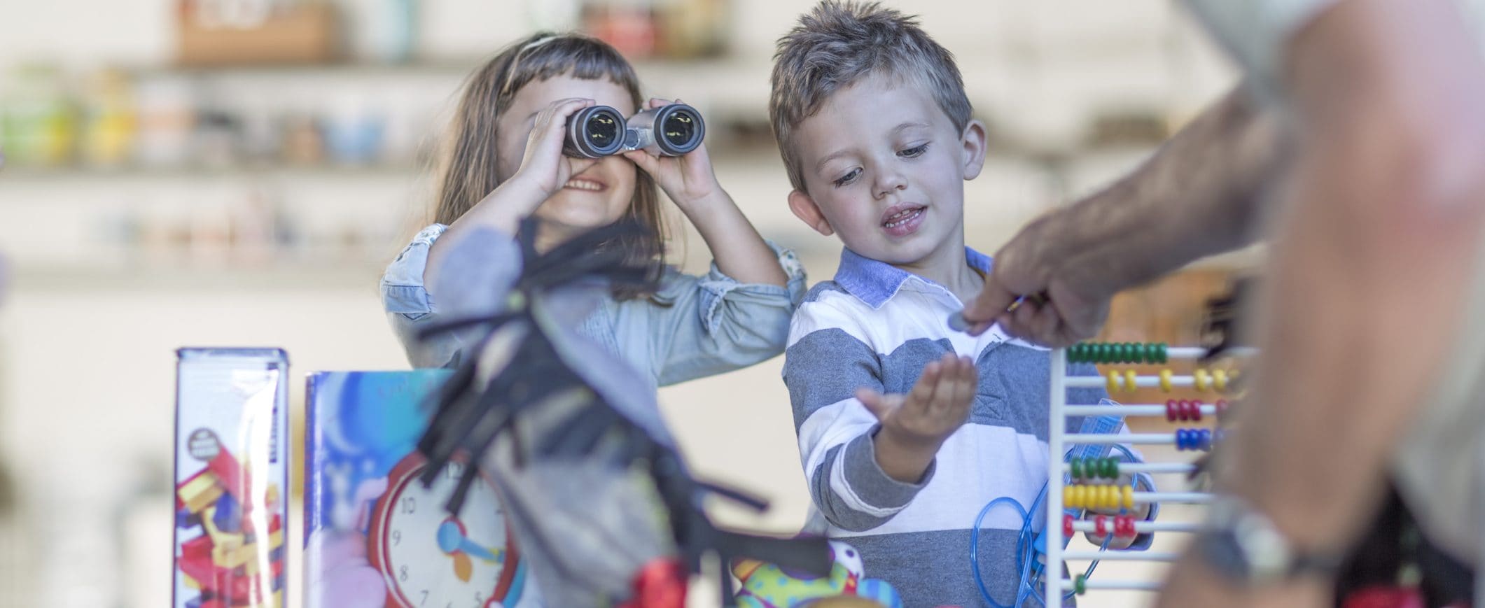 A young boy receiving money from a man, while a young girl standing next to him looks through binoculars.