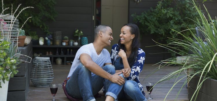 Couple enjoying wine in their backyard instead of going out to dinner as a way to save money