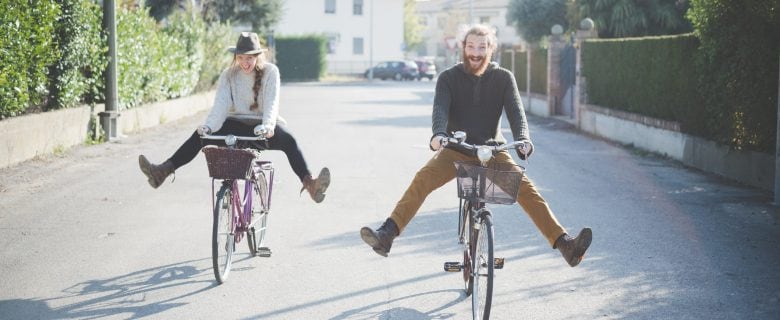 A man and a woman having fun on their bikes.