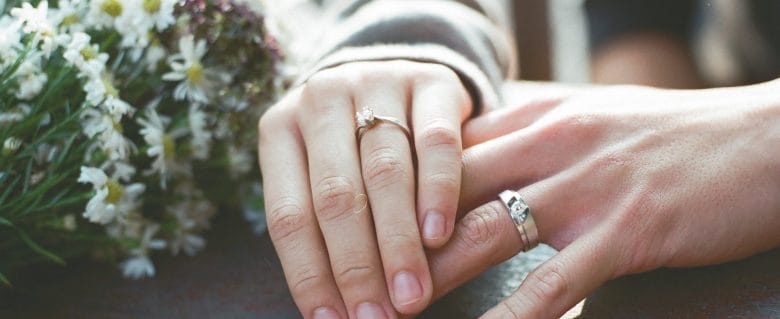 Bride and groom showing off their rings in a close-up shot of their hands.