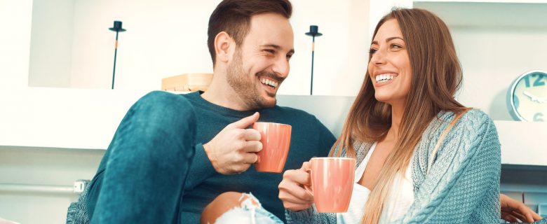 A man and a woman enjoy coffee together in their living room.