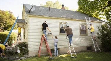 Group of 5 people painting the outside of a house.