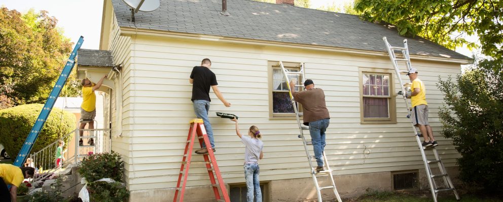 Group of 5 people painting the outside of a house.