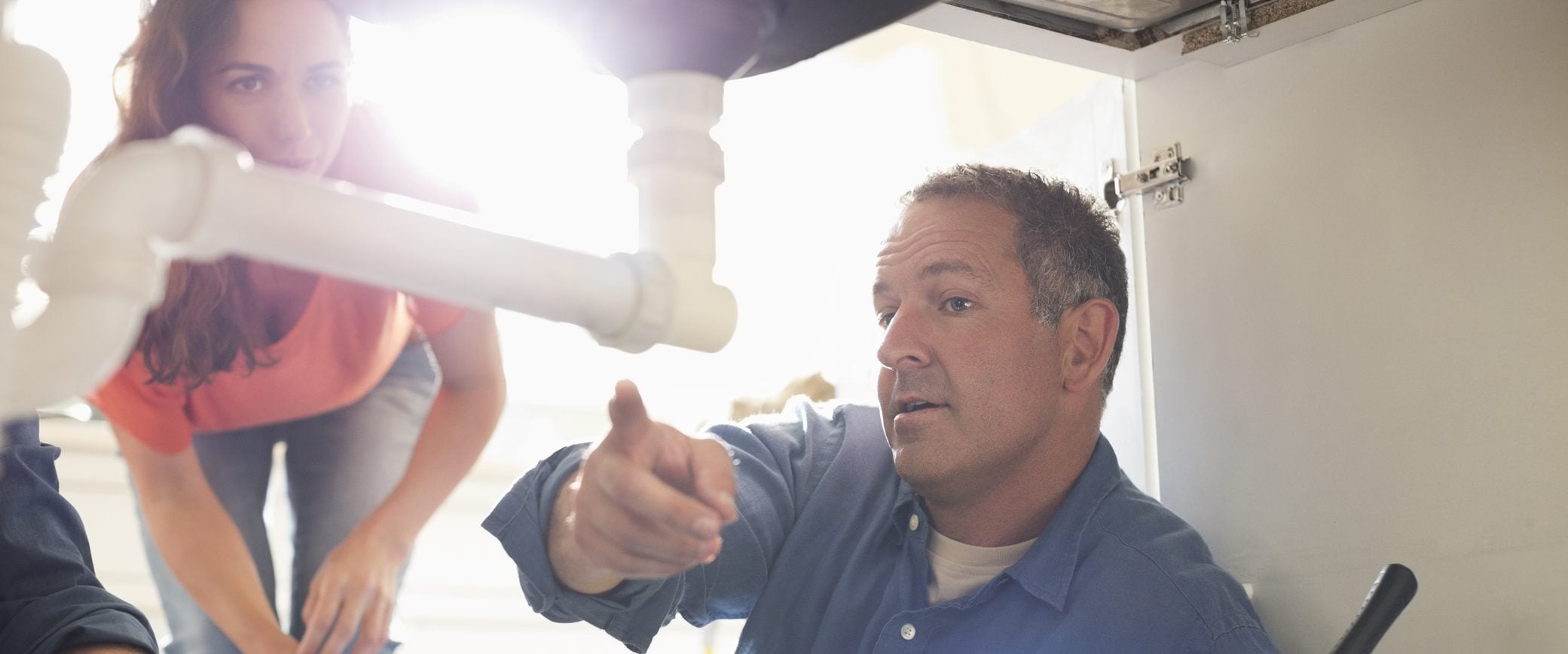 A plumber shows the homeowner what's wrong with her sink.