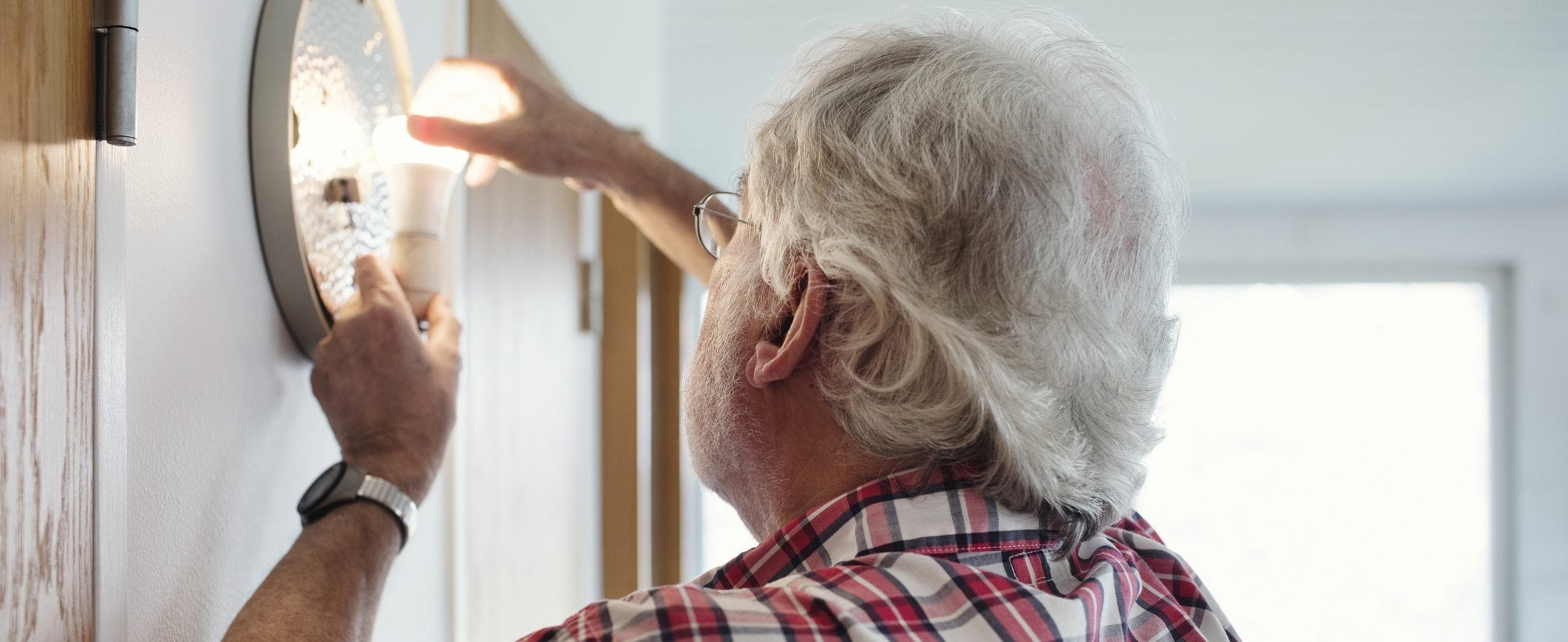 Man installs energy efficient light bulbs to help save money