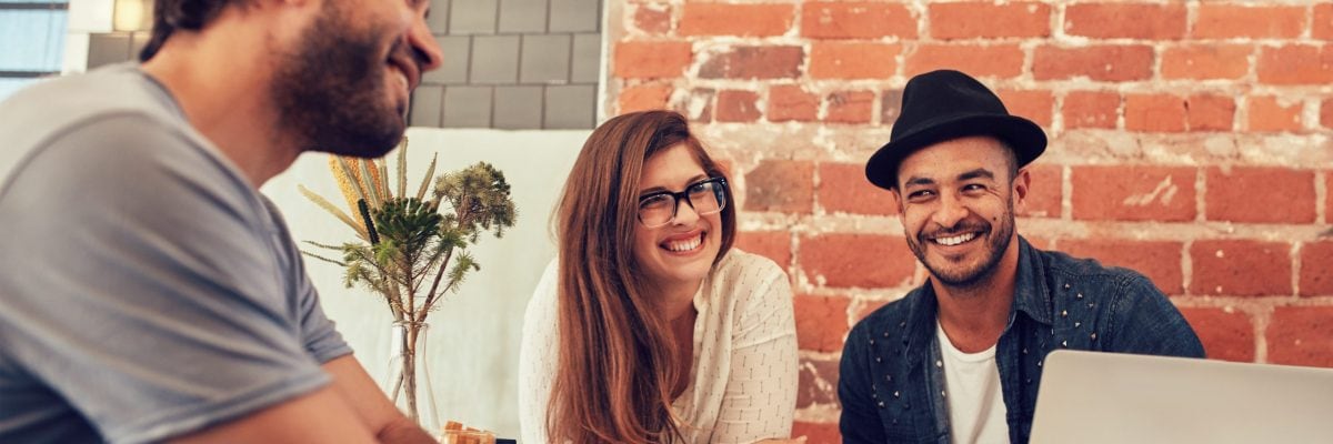 Two men and a woman talking and laughing outside.