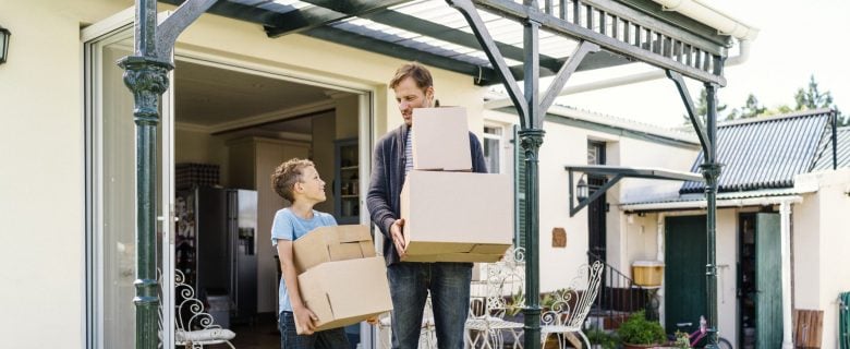 A man and his son carrying boxes as they move out of their home.